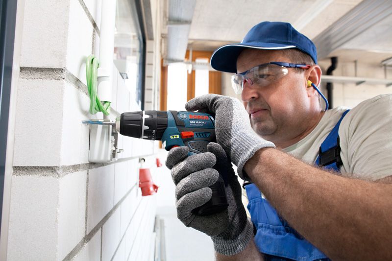 GSB 12V-15 ผู้ที่สวมอุปกรณ์ด้านความปลอดภัยใช้สว่านกระแทกไร้สายแบบติดผนัง.