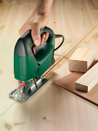 คนงานกำลังเลื่อนจิ๊กซอว์ไปตามเส้นที่ทำเครื่องหมายไว้เพื่อตัดไม้อัด.