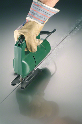 บุคคลที่สวมอุปกรณ์ความปลอดภัยใช้เลื่อยจิ๊กซอว์ตัดโลหะเป็นเส้นตรง.