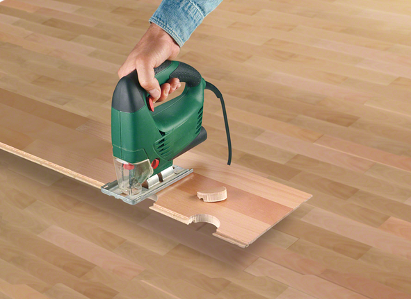 คนใช้จิ๊กซอว์ตัดรอยบากเป็นวงกลมในแผ่นไม้.