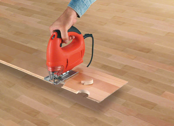 จิ๊กซอว์กำลังตัดรอยบากโค้งบนพื้นไม้ลามิเนต.