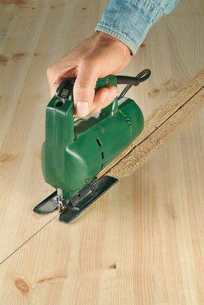 คนๆ หนึ่งกำลังใช้จิ๊กซอว์ตัดแผ่นไม้ให้เป็นเส้นตรง.