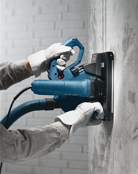 บุคคลที่สวมอุปกรณ์ด้านความปลอดภัยกำลังใช้งานเครื่องไล่ผนังเพื่อตัดร่องในคอนกรีต.