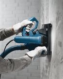 บุคคลที่สวมอุปกรณ์ด้านความปลอดภัยกำลังใช้งานเครื่องไล่ผนังเพื่อตัดร่องในคอนกรีต.