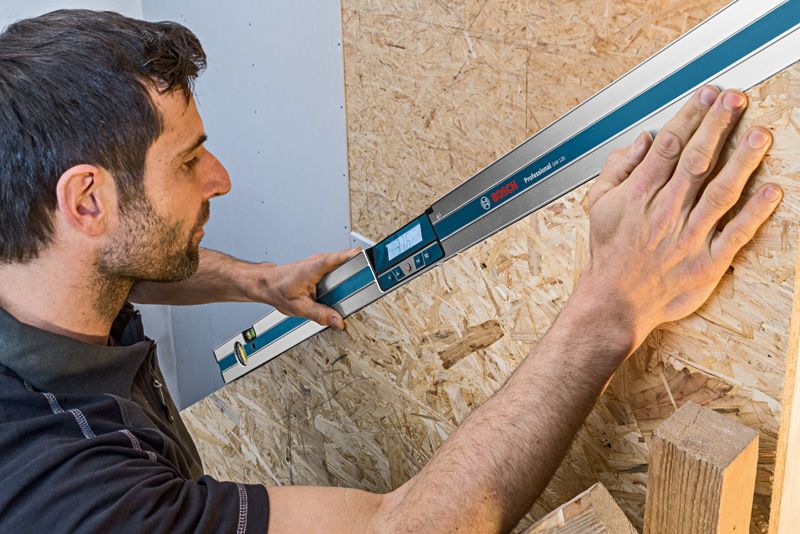 ผู้ใช้เครื่องวัดความเอียงแบบดิจิตอลเพื่อวัดมุมของพื้นผิวไม้.