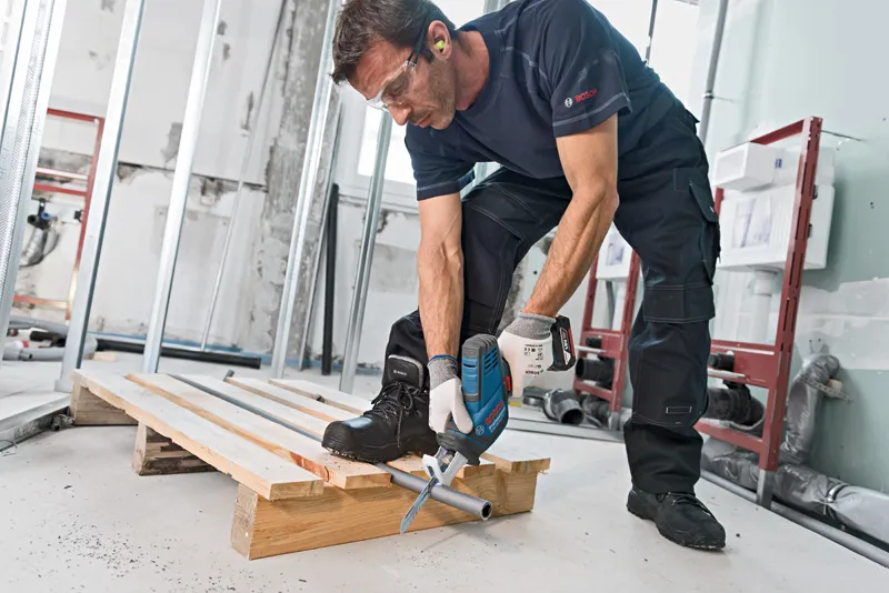 บุคคลที่สวมอุปกรณ์ด้านความปลอดภัยใช้เลื่อยตัดโลหะแบบลูกสูบ.