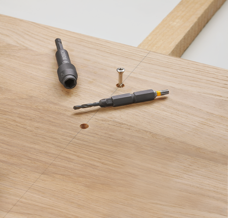 ดอกสว่านและดอกไขควงวางอยู่บนกระดานไม้ข้างสกรู.