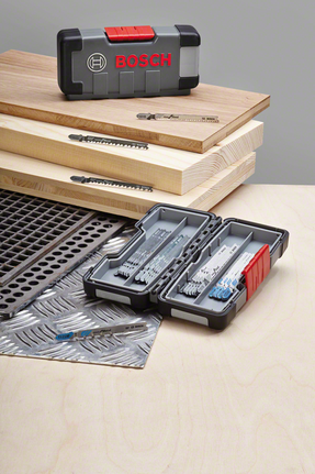 ชุดใบเลื่อยจิ๊กซอว์จัดแสดงบนแผ่นไม้และแผ่นโลหะ โดยใบเลื่อยจัดเก็บเป็นระเบียบในกล่อง