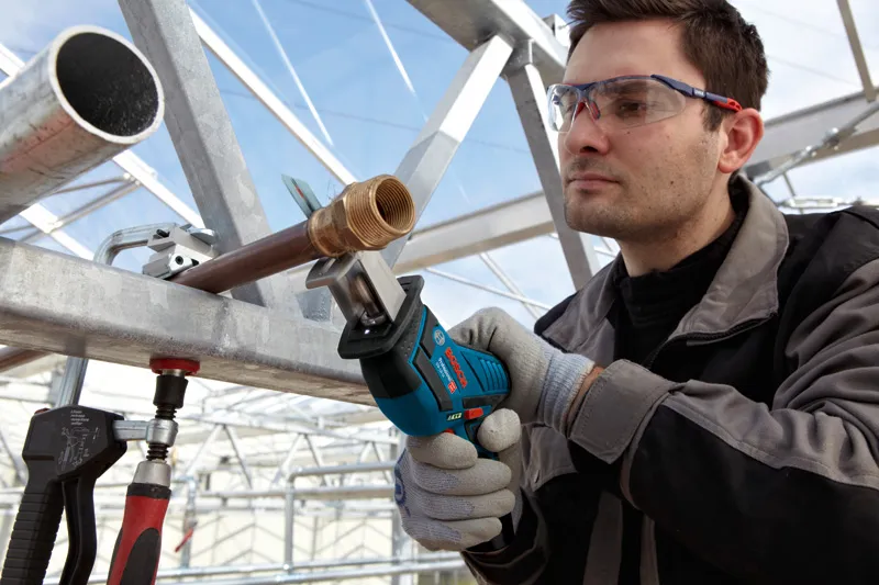 บุคคลที่สวมอุปกรณ์ด้านความปลอดภัยใช้เลื่อยตัดโลหะแบบไร้สาย.