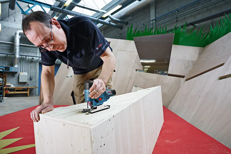 คนใช้จิ๊กซอว์ไร้สายตัดไม้ในโรงงาน.