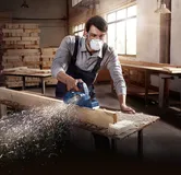 คนสวมอุปกรณ์ความปลอดภัยกำลังไสคานไม้ในโรงงาน