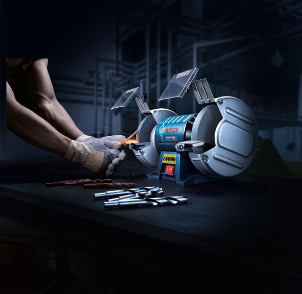 บุคคลที่สวมอุปกรณ์ป้องกันความปลอดภัยกำลังลับคมดอกสว่านด้วยเครื่องเจียรแท่นแบบล้อคู่