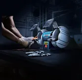 บุคคลที่สวมอุปกรณ์ป้องกันความปลอดภัยกำลังลับคมดอกสว่านด้วยเครื่องเจียรแท่นแบบล้อคู่