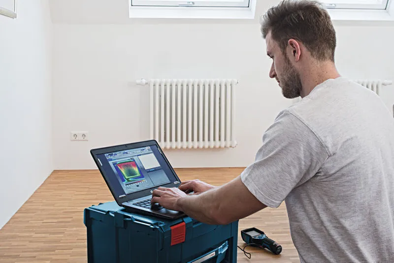 GTC 400 C บุคคลกำลังวิเคราะห์ข้อมูลกล้องถ่ายเทอร์มอลบนแล็ปท็อปในห้องที่มีหม้อน้ำ.