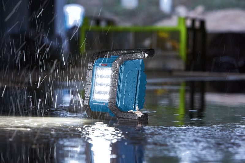 ไฟทำงานทำงานบนพื้นเปียกขณะฝนตกหนักในพื้นที่ก่อสร้าง.