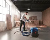 ผู้ที่สวมอุปกรณ์ความปลอดภัยใช้เครื่องดูดฝุ่นในโรงงานไม้.