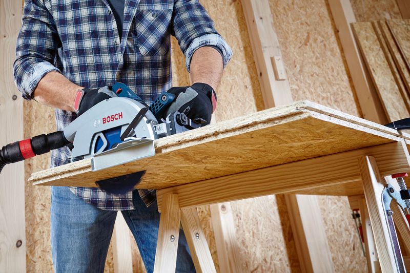 บุคคลที่สวมอุปกรณ์ความปลอดภัยใช้เลื่อยวงเดือนตัดแผ่นไม้.