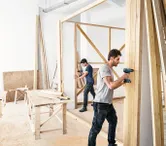 ชายสองคนกำลังสร้างกำแพงไม้.