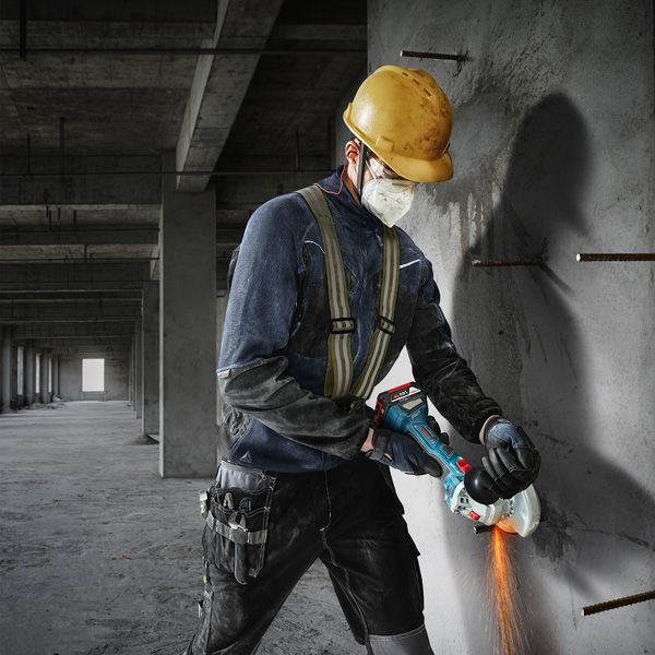 บุคคลที่สวมอุปกรณ์ด้านความปลอดภัยกำลังตัดคอนกรีตด้วยเครื่องเจียร.