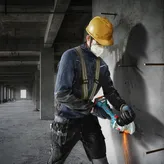 บุคคลที่สวมอุปกรณ์ด้านความปลอดภัยกำลังตัดคอนกรีตด้วยเครื่องเจียร.