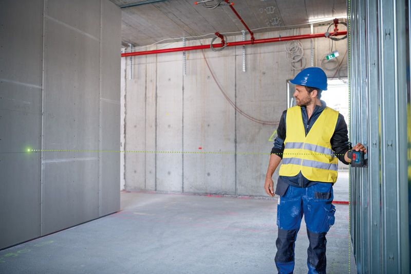 บุคคลที่สวมอุปกรณ์ด้านความปลอดภัยใช้เครื่องมือปรับระดับเลเซอร์บนไซต์ก่อสร้าง.