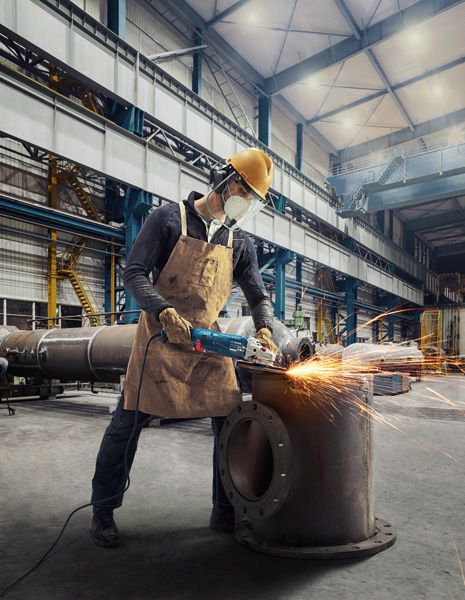 บุคคลที่สวมอุปกรณ์ด้านความปลอดภัยใช้เครื่องเจียรไฟฟ้าตัดโลหะ ทำให้เกิดประกายไฟ.