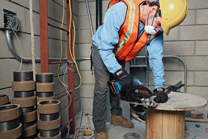 บุคคลที่สวมอุปกรณ์ความปลอดภัยกำลังตัดไม้ด้วยเลื่อยมือถือบนไซต์ก่อสร้าง.