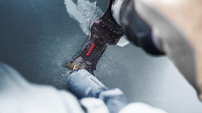 คนกำลังตัดท่อโลหะที่ทาสีด้วยใบเลื่อยตัดโลหะ