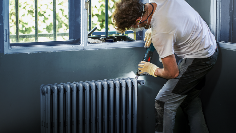 ผู้ที่สวมอุปกรณ์ด้านความปลอดภัยใช้สว่านไร้สายในการติดตั้งหม้อน้ำ