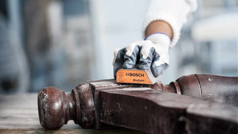 บุคคลที่สวมอุปกรณ์ความปลอดภัยขัดที่วางแขนเก้าอี้ไม้