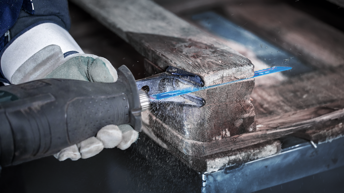 บุคคลที่สวมอุปกรณ์ด้านความปลอดภัยใช้เลื่อยตัดไม้พาเลท