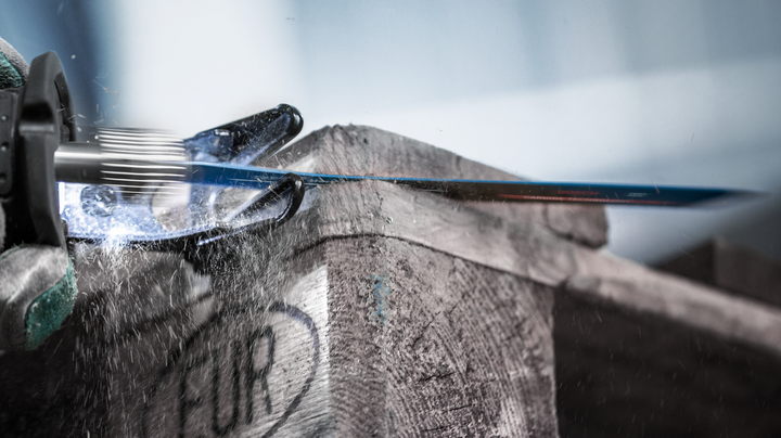 บุคคลที่สวมอุปกรณ์ความปลอดภัยใช้เลื่อยตัดโลหะตัดผ่านลังไม้