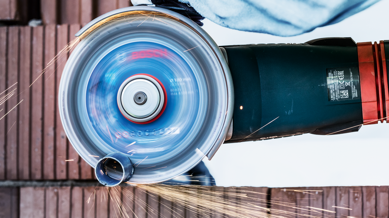 บุคคลที่สวมอุปกรณ์ความปลอดภัยกำลังใช้เครื่องเจียรไฟฟ้าตัดอิฐ ทำให้เกิดประกายไฟ