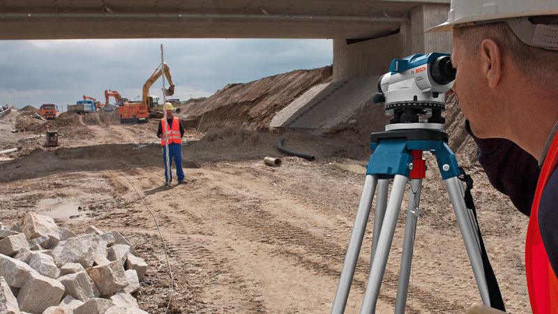 บุคคลที่สวมอุปกรณ์ความปลอดภัยใช้ระดับแสงในสถานที่ก่อสร้างถนน