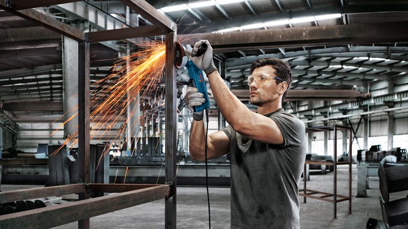 ชายกำลังบดโครงเหล็ก.