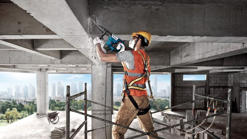 บุคคลที่สวมอุปกรณ์ด้านความปลอดภัยกำลังทำลายเสาคอนกรีตโดยใช้ค้อนทุบทำลาย.