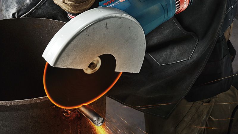 บุคคลที่สวมอุปกรณ์ด้านความปลอดภัยกำลังตัดท่อโลหะด้วยเครื่องเจียรมือถือ.