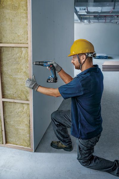 คนงานติดตั้งแผ่นยิปซัมบอร์ด.