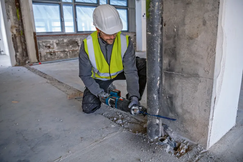 บุคคลที่สวมอุปกรณ์ด้านความปลอดภัยใช้เลื่อยตัดโลหะแบบลูกสูบ.