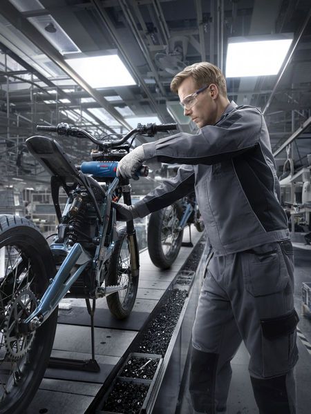 บุคคลที่สวมอุปกรณ์ความปลอดภัยกำลังประกอบโครงรถจักรยานยนต์ในโรงงานแห่งหนึ่ง.