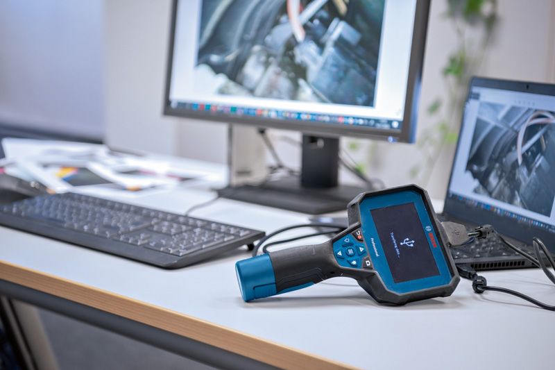 กล้องตรวจสอบที่เชื่อมต่อกับคอมพิวเตอร์บนโต๊ะทำงานสำนักงานเพื่อแสดงภาพเครื่องยนต์.