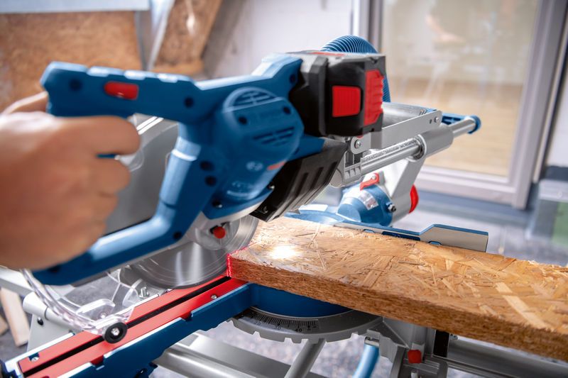 คนกำลังตัดไม้กระดานด้วยเลื่อยองศาไร้สายบนโต๊ะทำงาน.