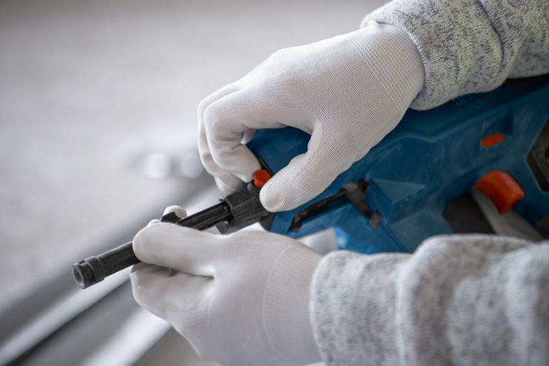 บุคคลที่สวมอุปกรณ์ด้านความปลอดภัยกำลังปรับเครื่องตอกตะปูคอนกรีตแบบไร้สาย.