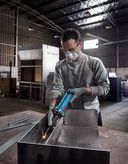 บุคคลที่สวมอุปกรณ์ความปลอดภัยกำลังบดโลหะภายในโรงงานอุตสาหกรรม.