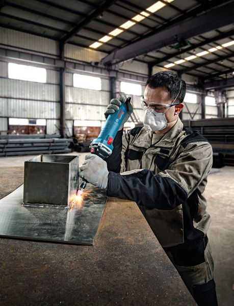 ผู้ที่สวมอุปกรณ์ด้านความปลอดภัยจะใช้เครื่องเจียรตรงกับแผ่นโลหะ.