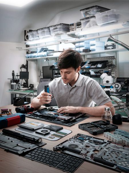 คนกำลังประกอบอุปกรณ์อิเล็กทรอนิกส์ด้วยไขควงไร้สายในโรงงาน.