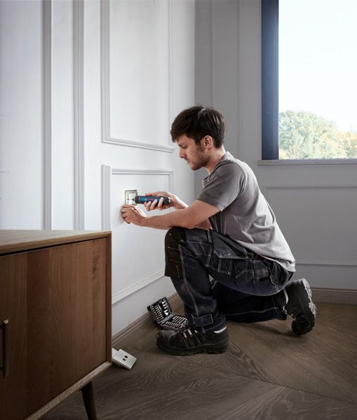 คนๆ หนึ่งกำลังติดตั้งฝาครอบเต้ารับไฟฟ้าโดยใช้ไขควงไร้สาย.