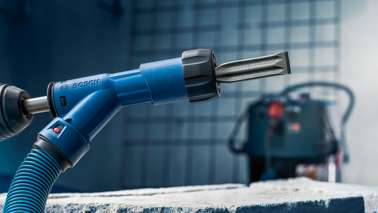 ค้อนโรตารี่พร้อมหัวสิ่ววางอยู่บนบล็อกคอนกรีตหยาบ