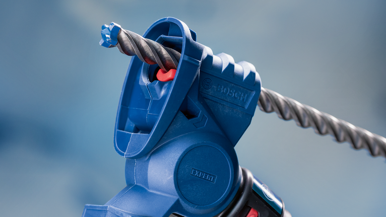 ภาพระยะใกล้ของอุปกรณ์เสริมเครื่องมือไฟฟ้าสีน้ำเงินที่ถือดอกสว่านเจาะปูน