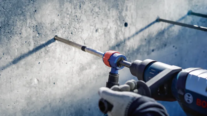 บุคคลที่สวมอุปกรณ์ความปลอดภัยกำลังเจาะเข้าไปในผนังคอนกรีต